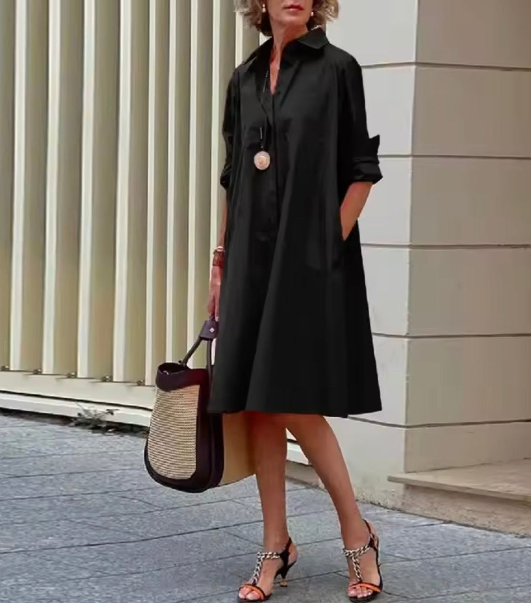 Woman wearing a classic black shirt dress with a collared neckline.