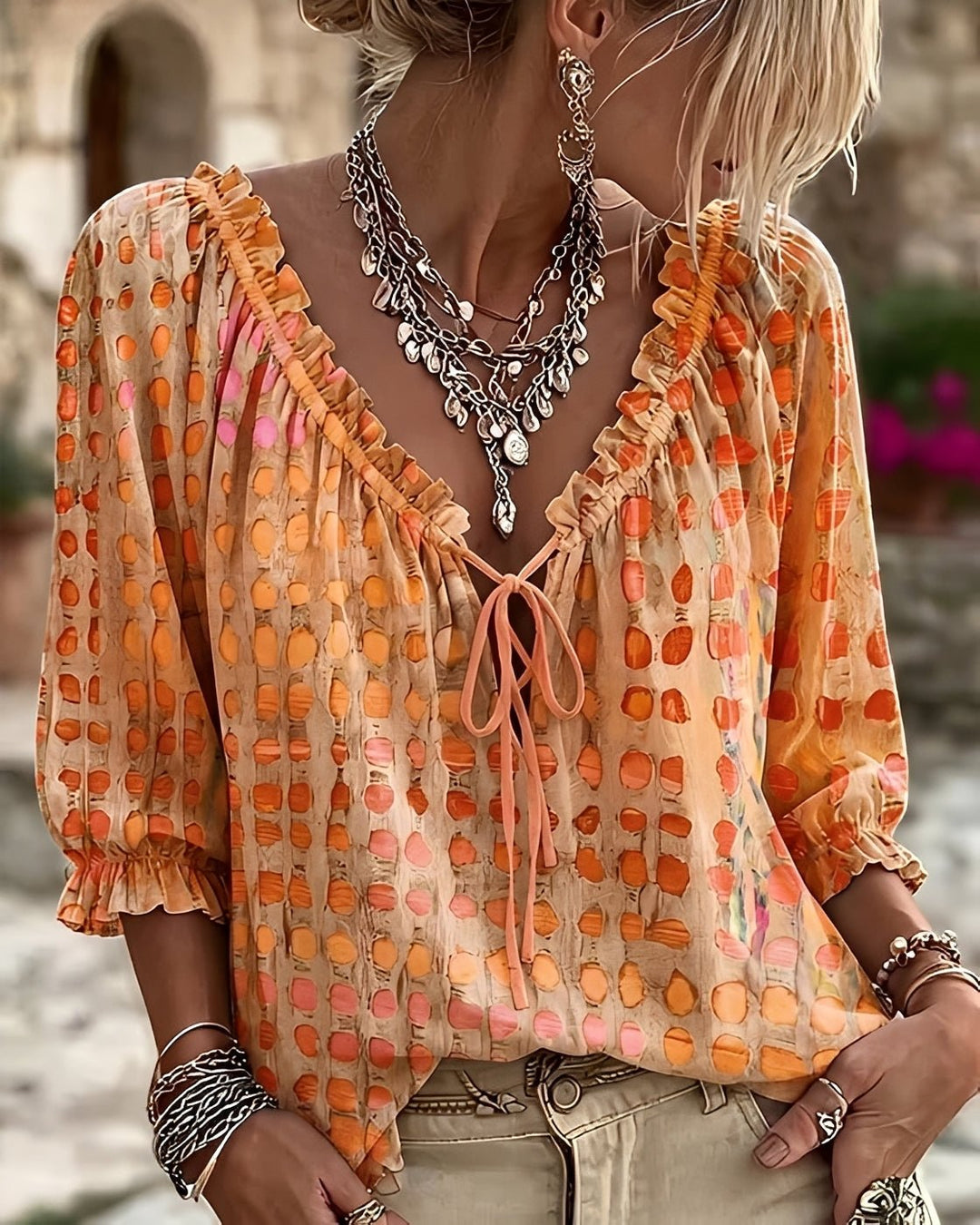 Woman wearing a vibrant orange polka-dot blouse with tie-neck detail