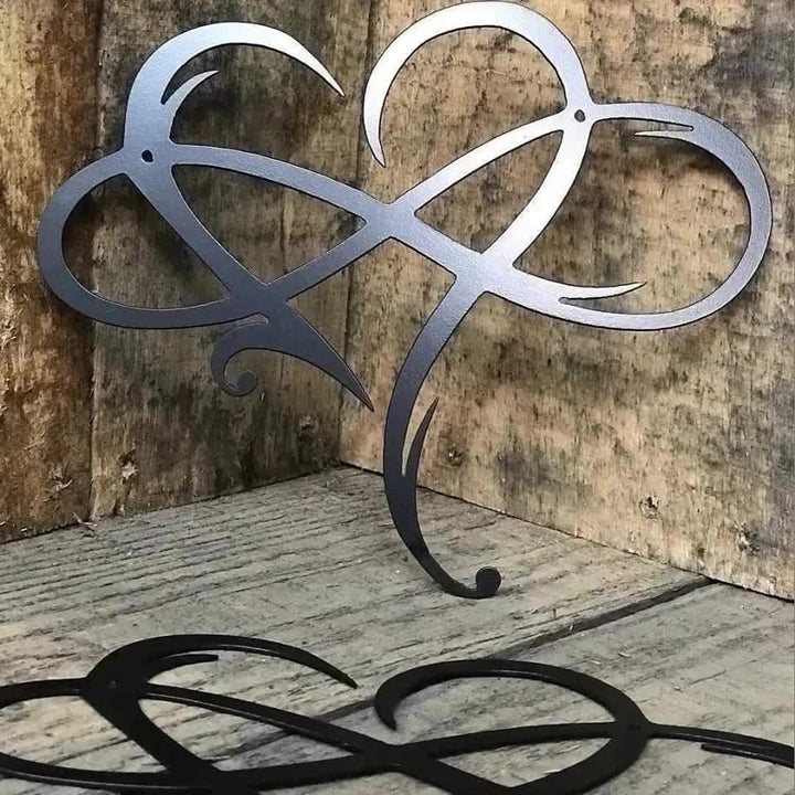 Close-up of the black metal heart infinity sculpture against a rustic wooden background
