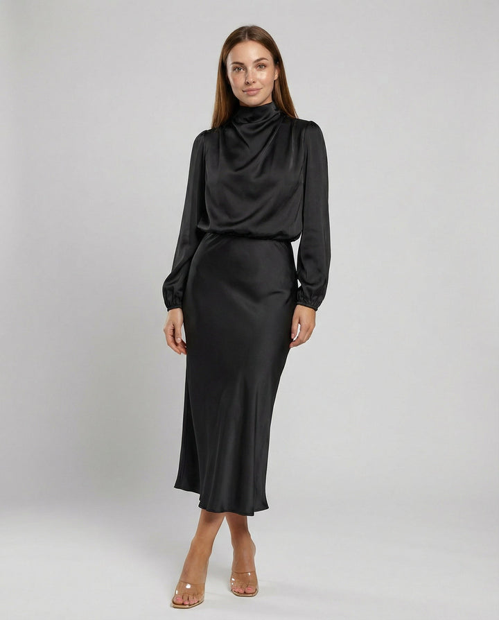 Model wearing a black long-sleeve midi dress with heels in a studio setting