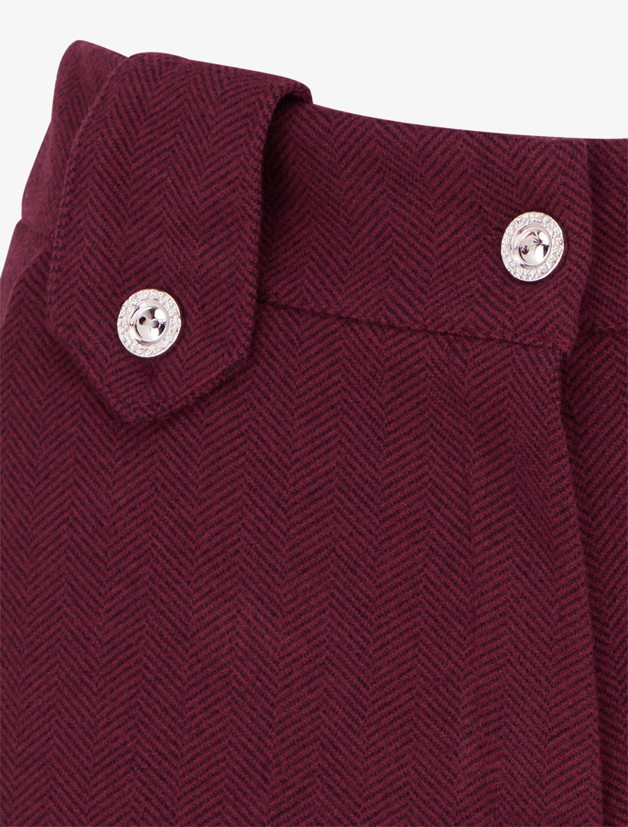 Close-up of textured fabric and decorative button detail on burgundy shorts