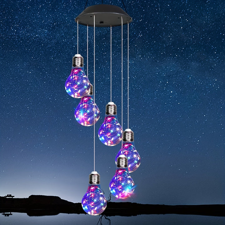 Solar light bulb wind chime hanging outdoors at night with glowing multi-colored LEDs