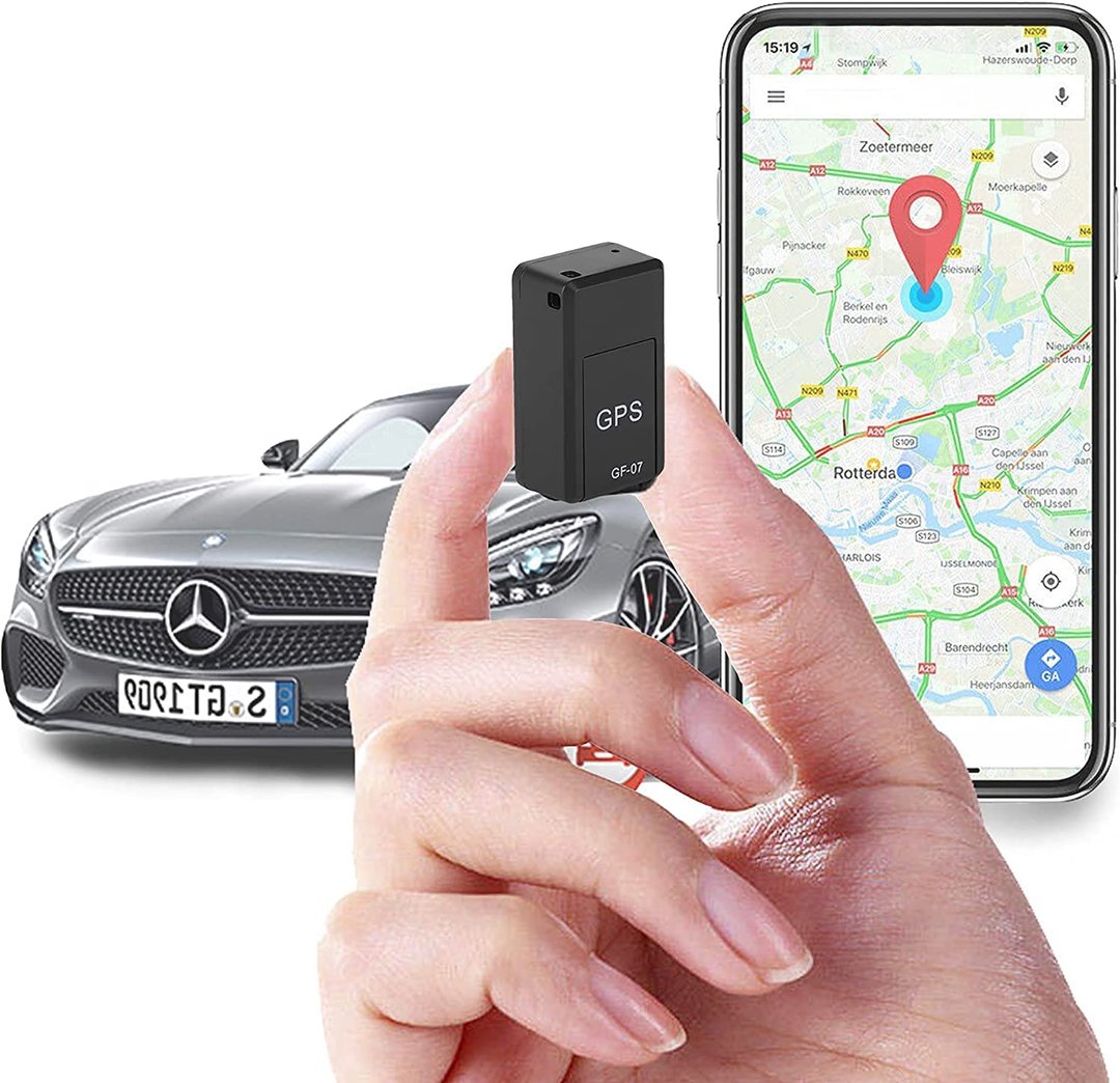 Mini magnetic GPS tracker held in hand in front of a car and smartphone map