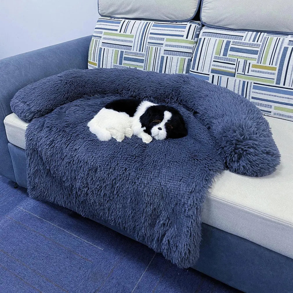 Navy plush pet blanket bed resting on a fabric sofa with a toy dog