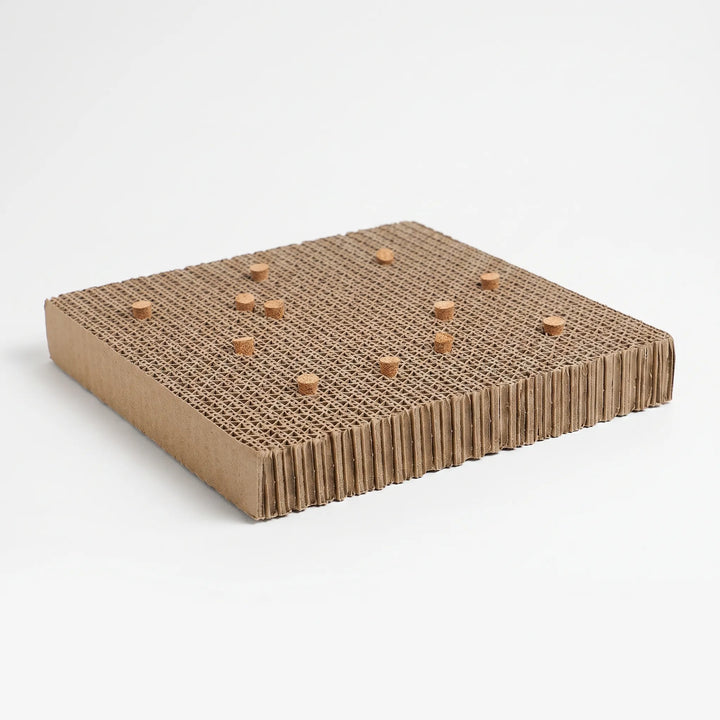 Textured cardboard bird chew platform with small wooden inserts on a white background