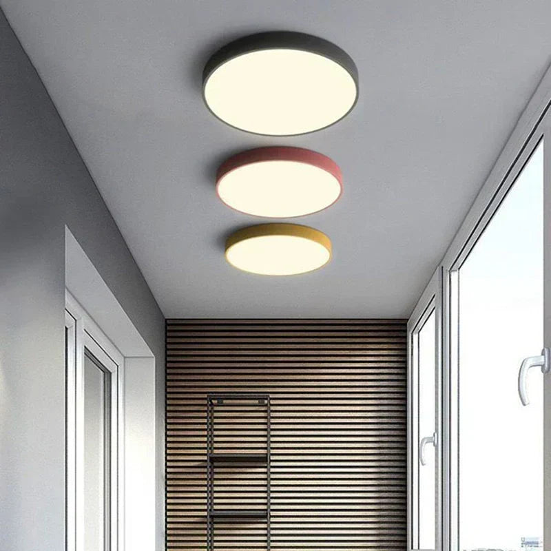 Minimalist round LED ceiling lamps with black, pink, and yellow frames in a hallway