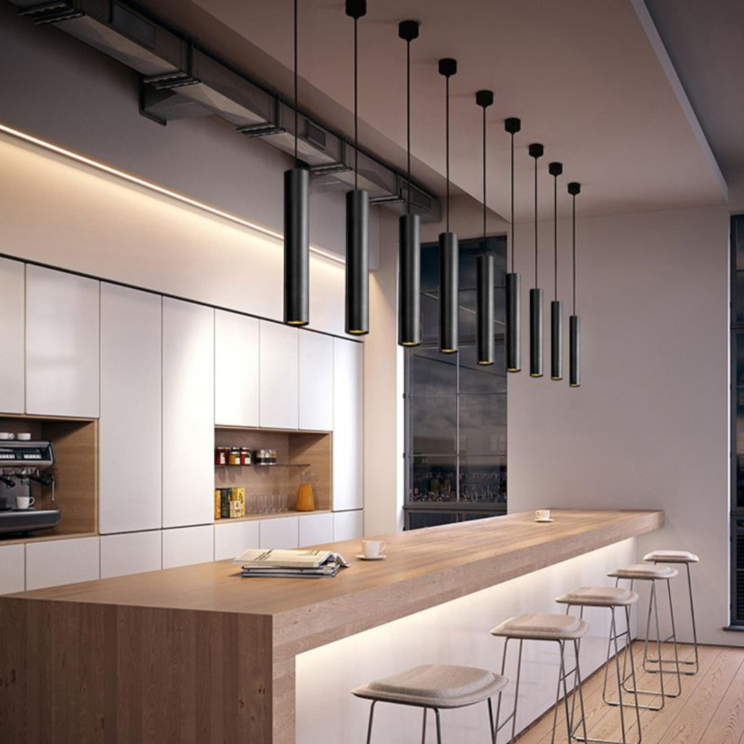 Modern cylindrical pendant lamp suspended over a dining table, providing sleek interior lighting.