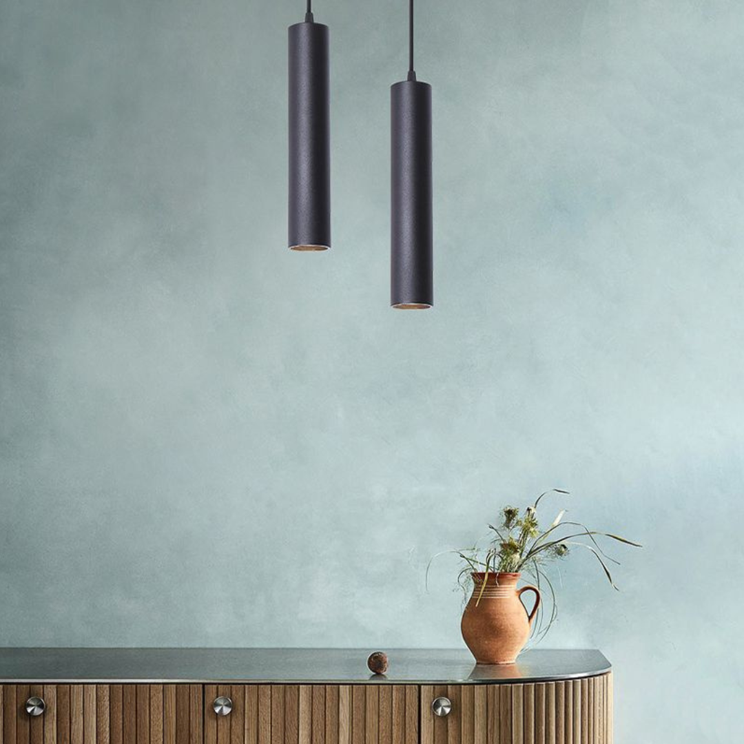 Two modern cylindrical pendant lamps installed above a wooden sideboard