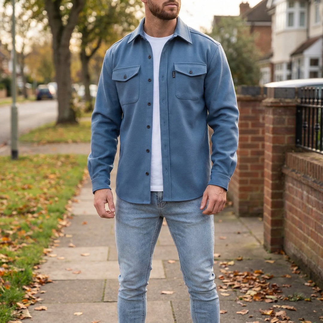 Man wearing a blue long-sleeved overshirt over a white t-shirt outdoors