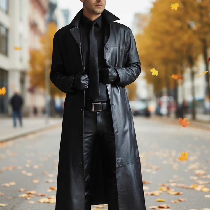 Man wearing a long black trench coat outdoors during autumn