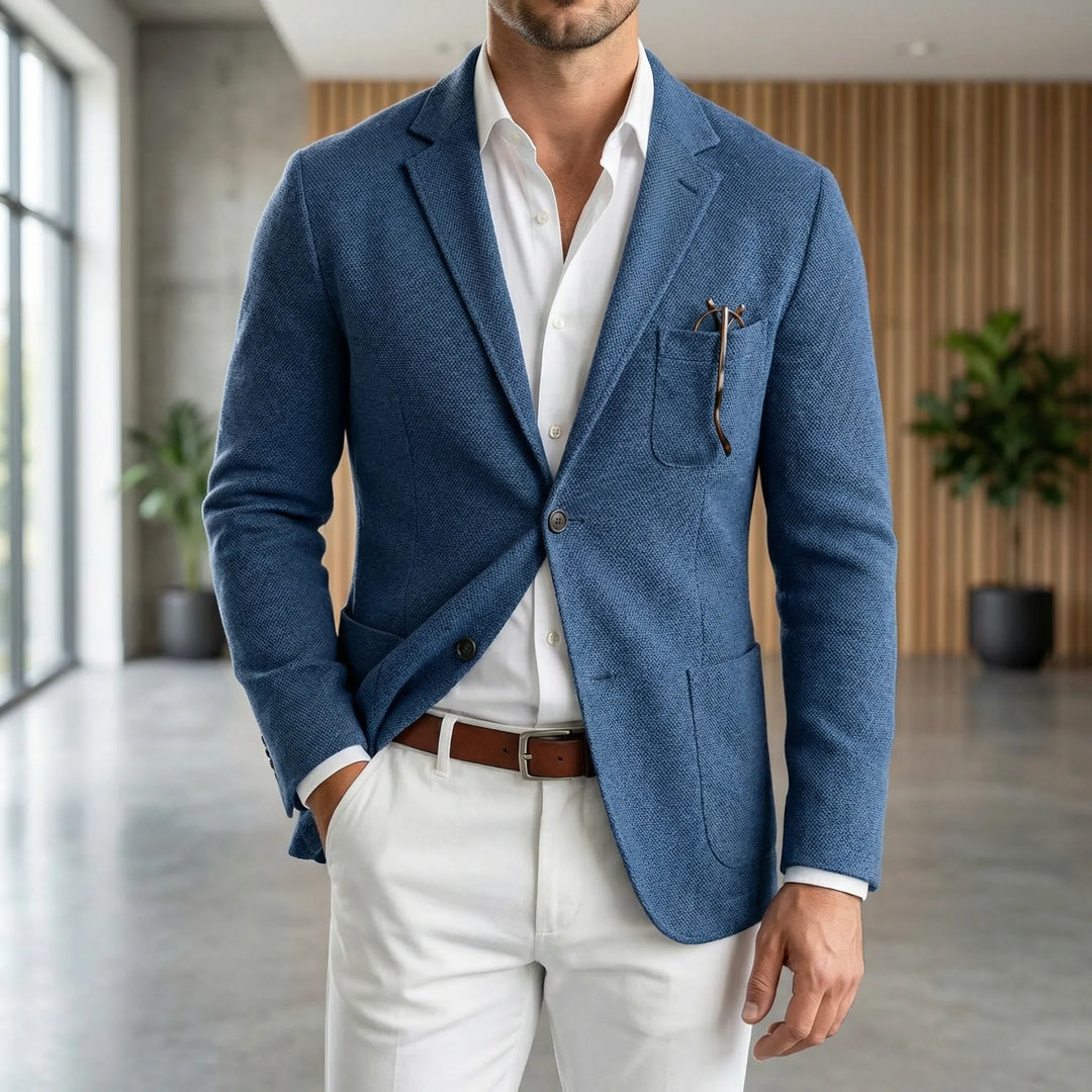 Man wearing a blue lightweight casual blazer with white trousers and brown belt