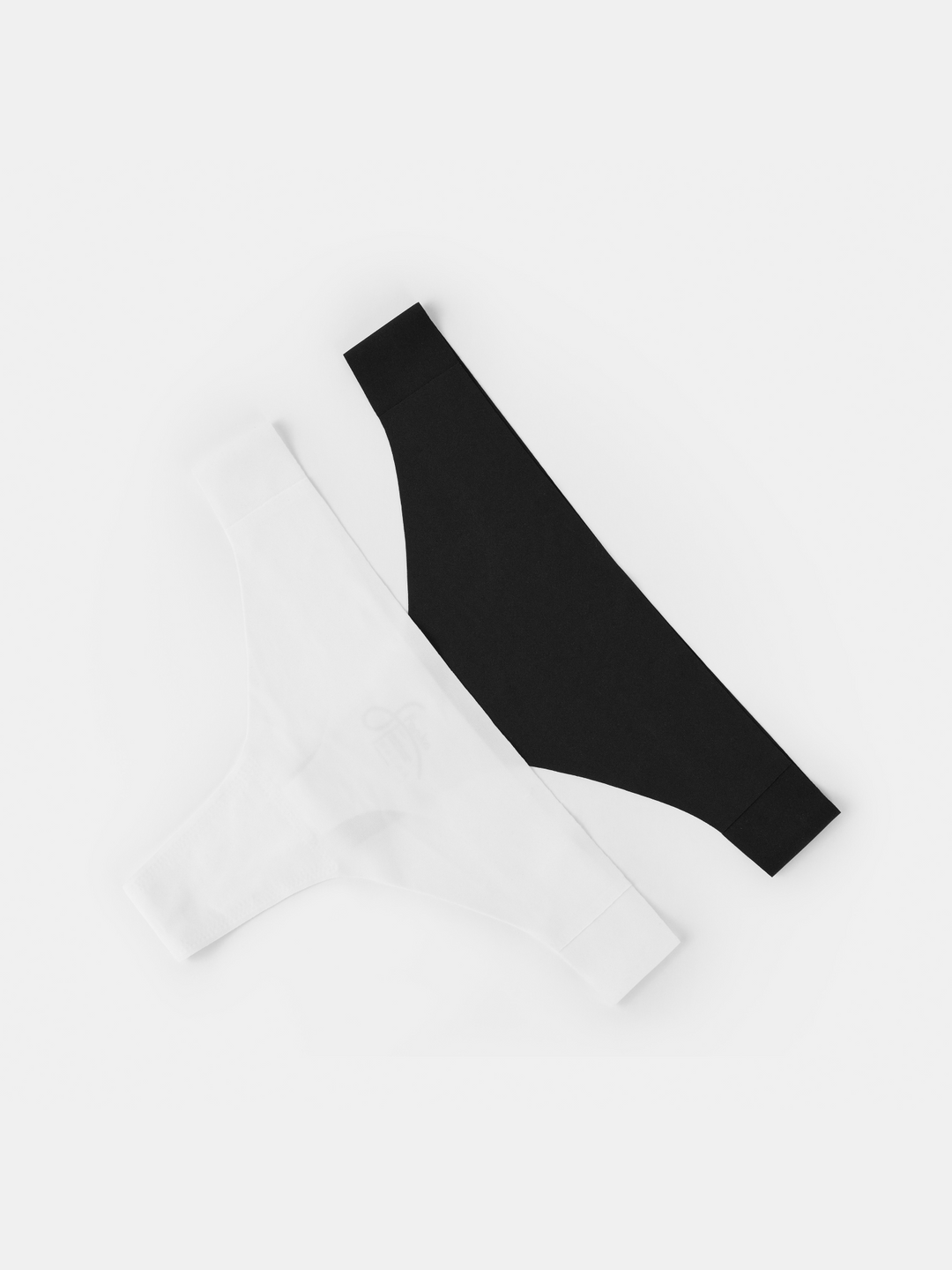 Black and white seamless thongs laid out flat on a neutral background