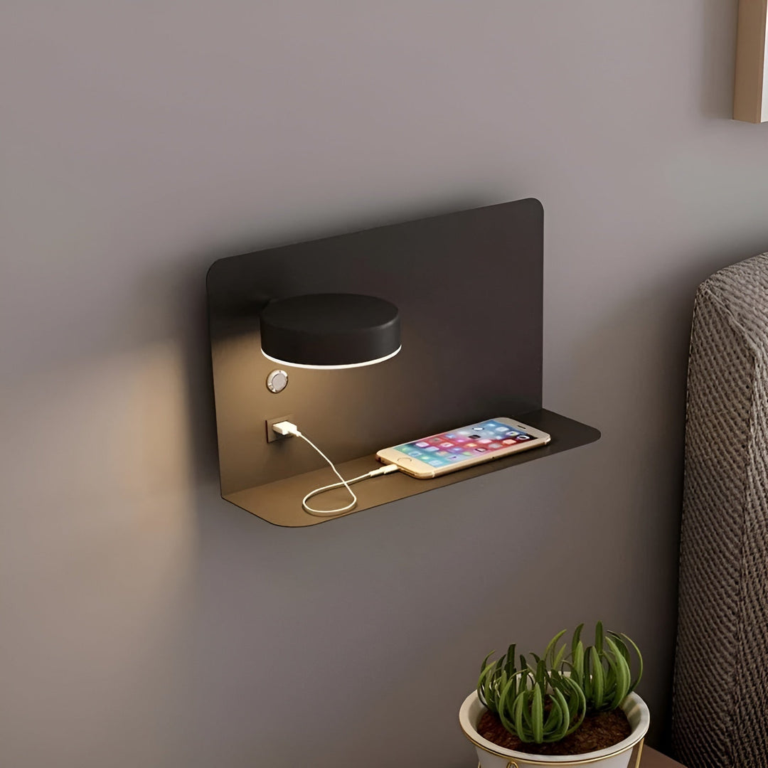Black modern LED wall sconce mounted on wall with phone charging on shelf