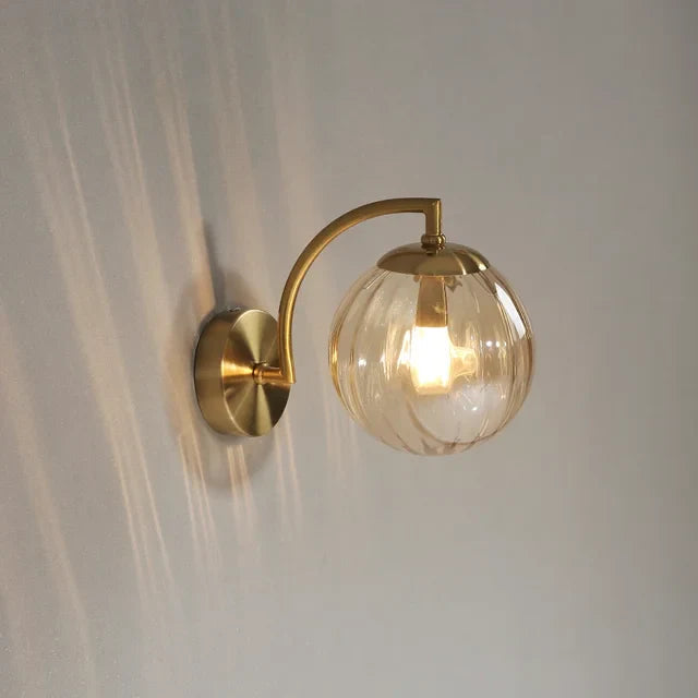 Amber glass globe wall sconce with warm light glowing