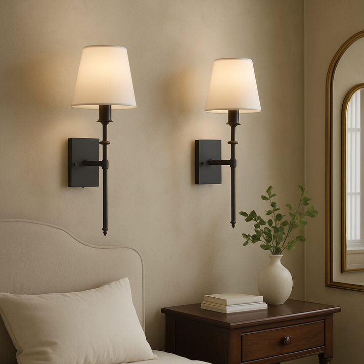 Two minimalist black wired wall sconces mounted above a bed in a modern bedroom setting.