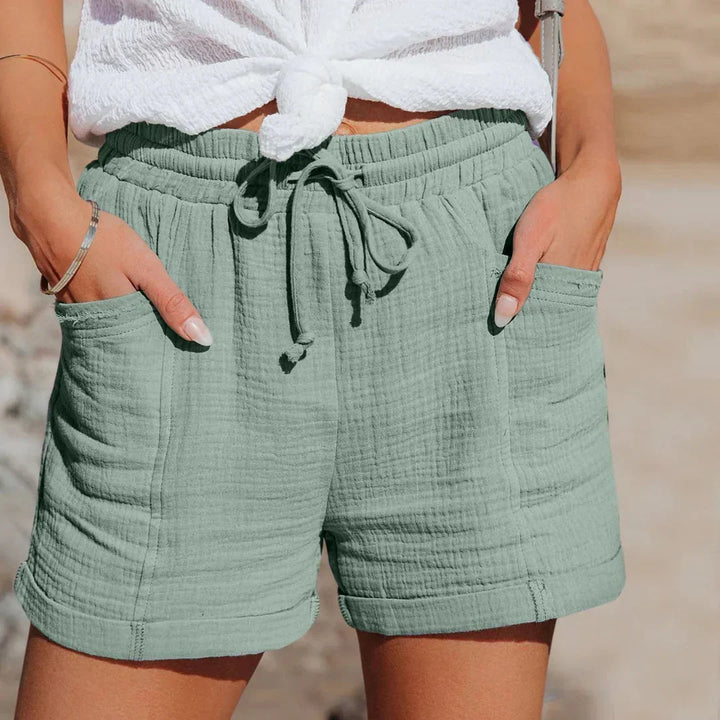 Woman wearing green lightweight summer shorts with drawstring waist at the beach