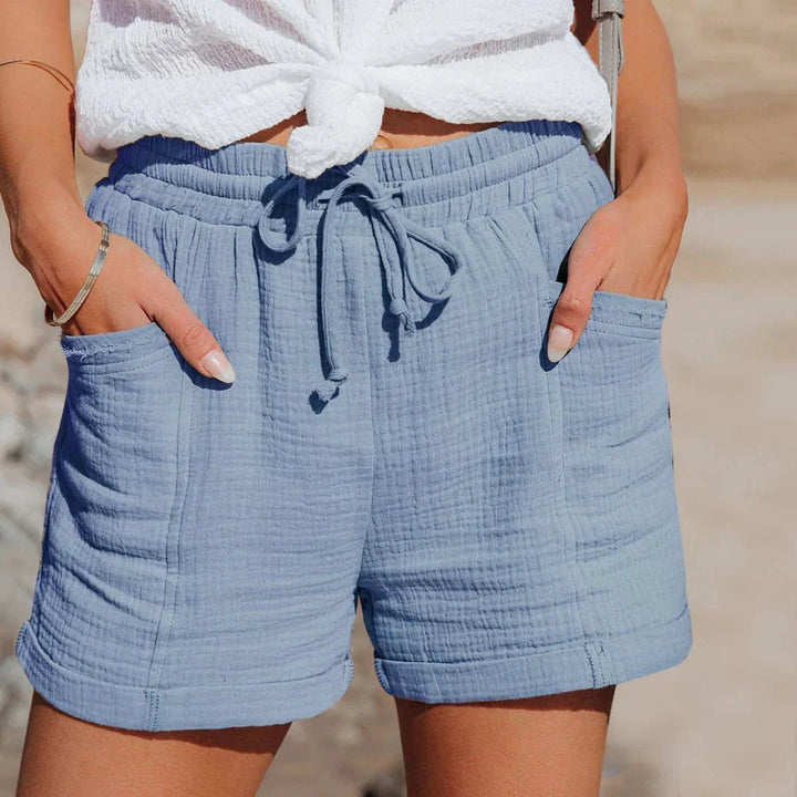 Woman wearing blue lightweight summer shorts with drawstring waist at the beach