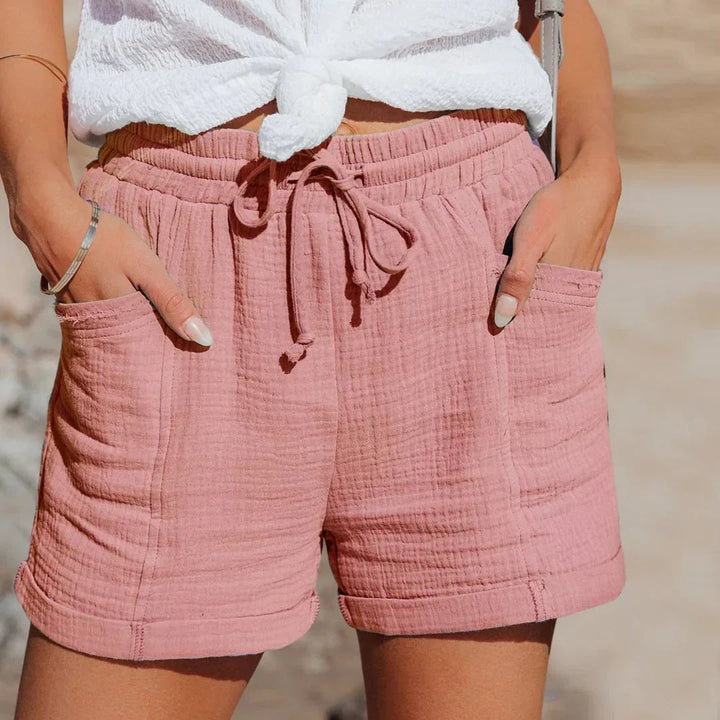 Woman wearing pink lightweight summer shorts with drawstring waist at the beach