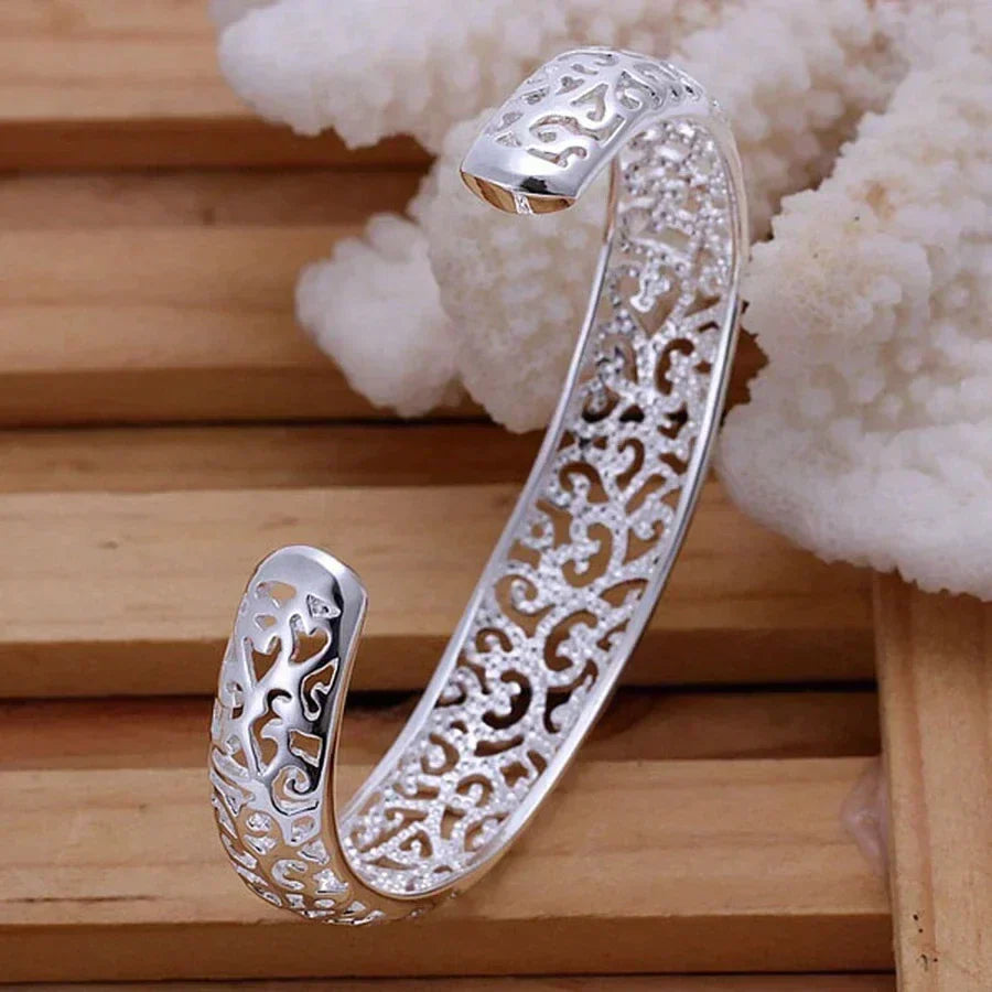 Adjustable silver cuff bracelet viewed from the side, demonstrating its sleek profile and finish.