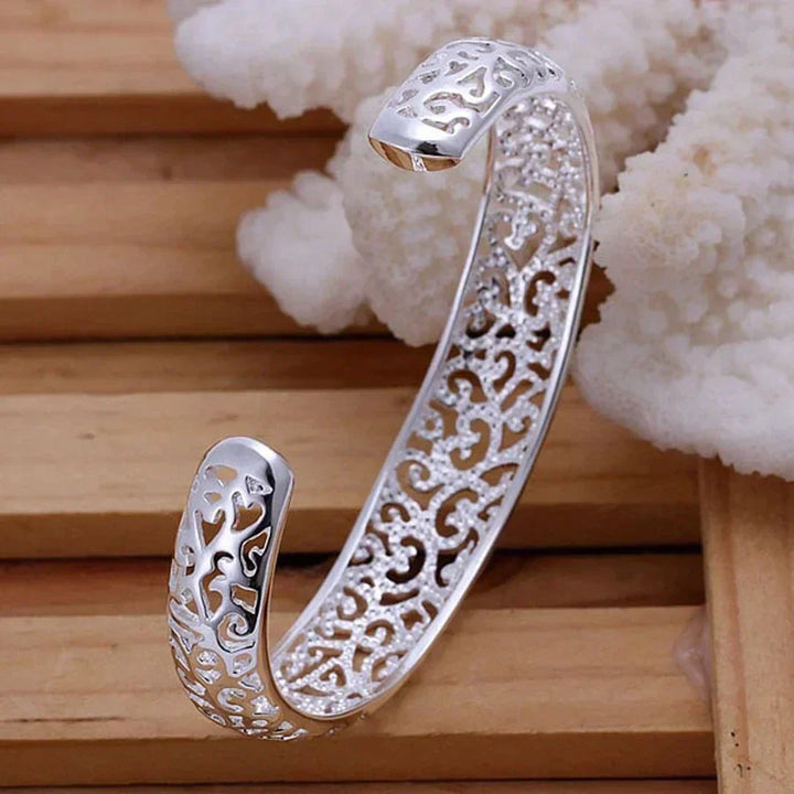 Adjustable silver cuff bracelet viewed from the side, demonstrating its sleek profile and finish.