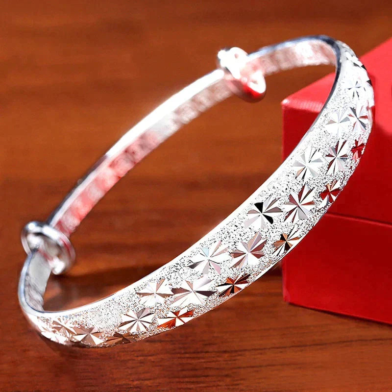 Elegant silver star bangle displayed next to a red gift box