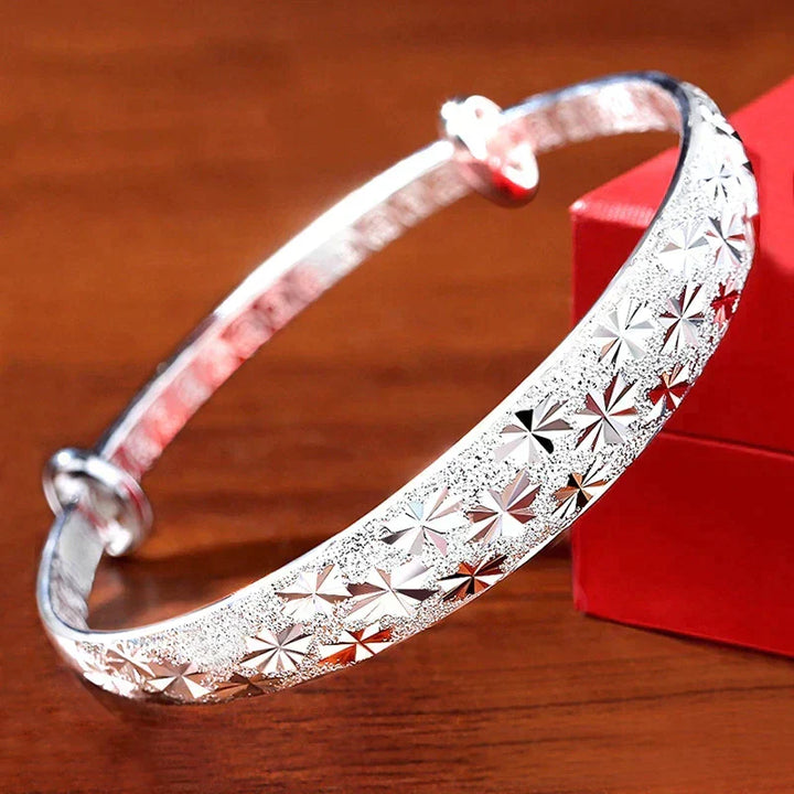 Elegant silver star bangle displayed next to a red gift box