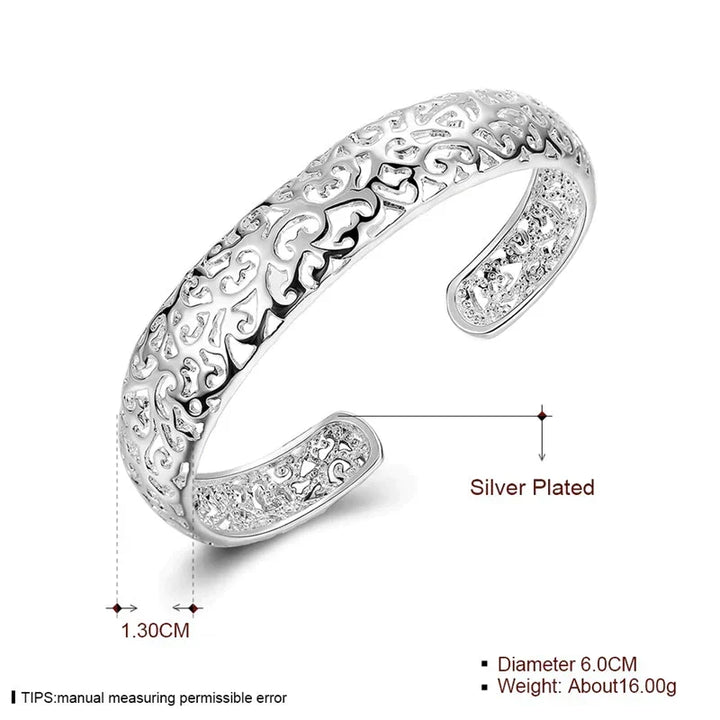 Womens jewelry piece: a wide silver filigree bracelet styled elegantly on a wrist.