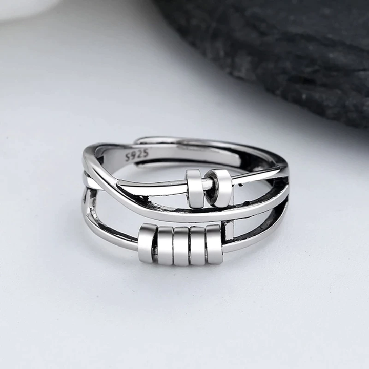 Sterling silver spinner ring featuring rolling beads and an adjustable open band design.