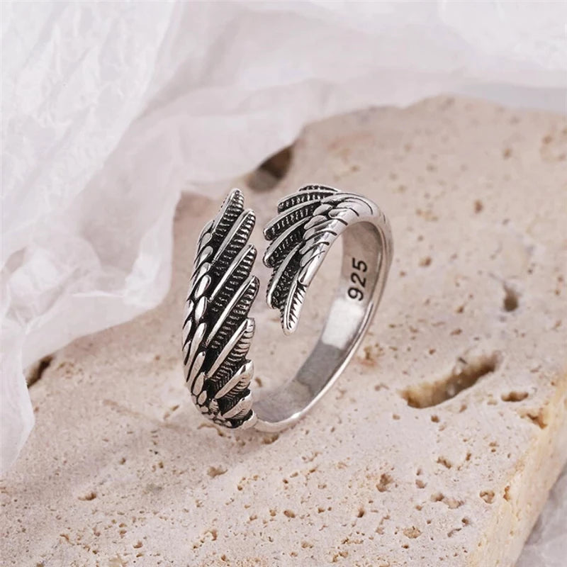 Close-up of the adjustable 925 silver feather wing ring on a textured surface