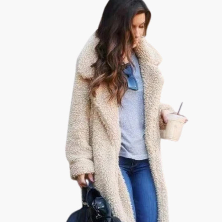 Woman wearing cream long teddy coat with lapel collar holding a coffee cup
