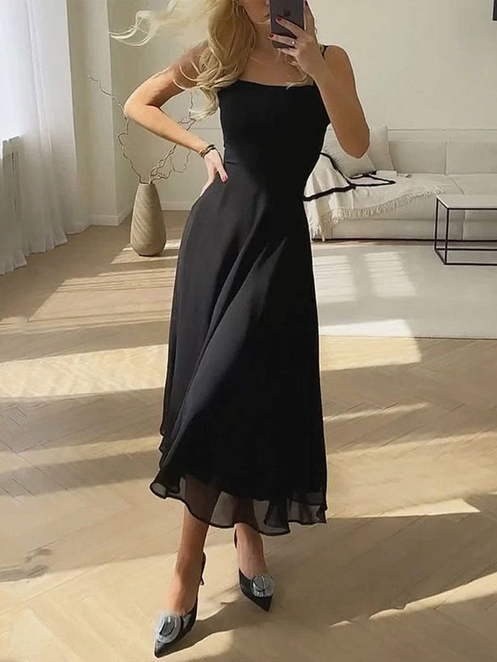 Woman wearing a black square neck sleeveless A-line midi dress indoors