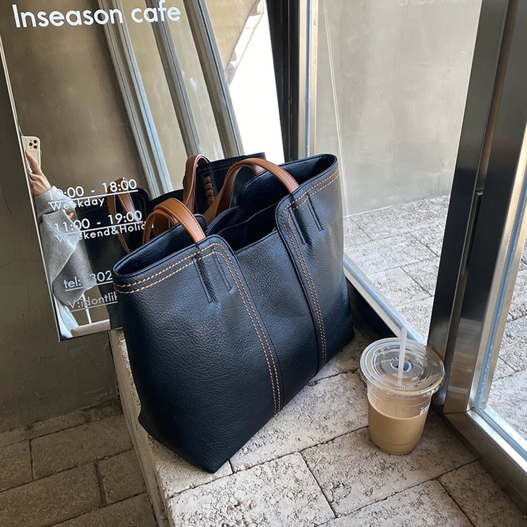 Model carrying women's minimalist shoulder bag as an everyday tote