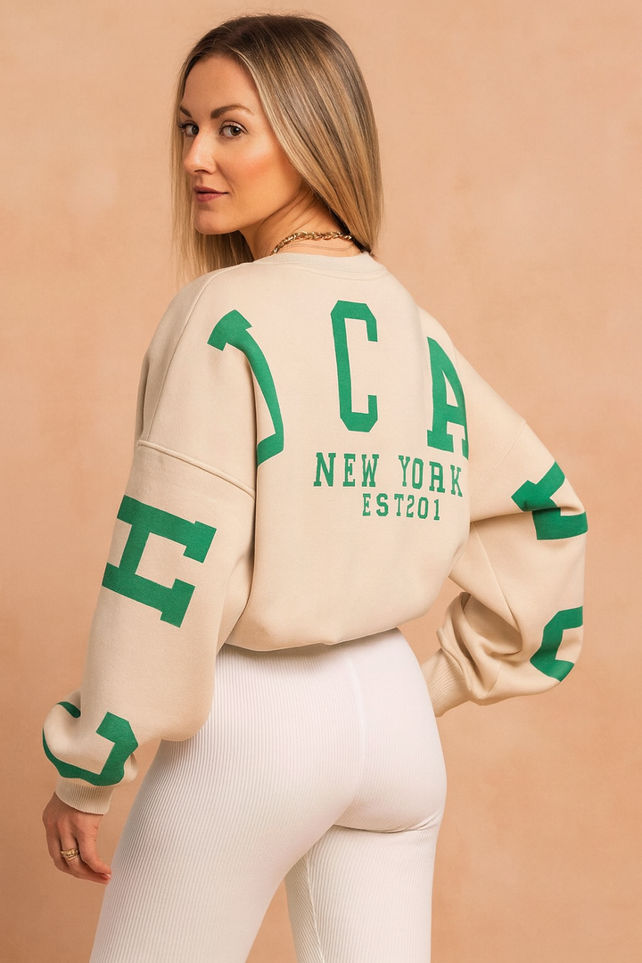 Back view of woman wearing beige graphic pullover sweater