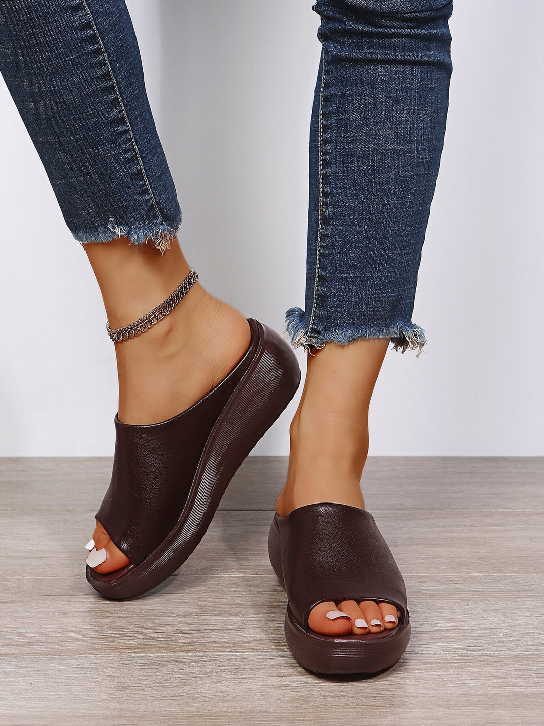 Woman wearing brown ergonomic comfort slippers paired with jeans