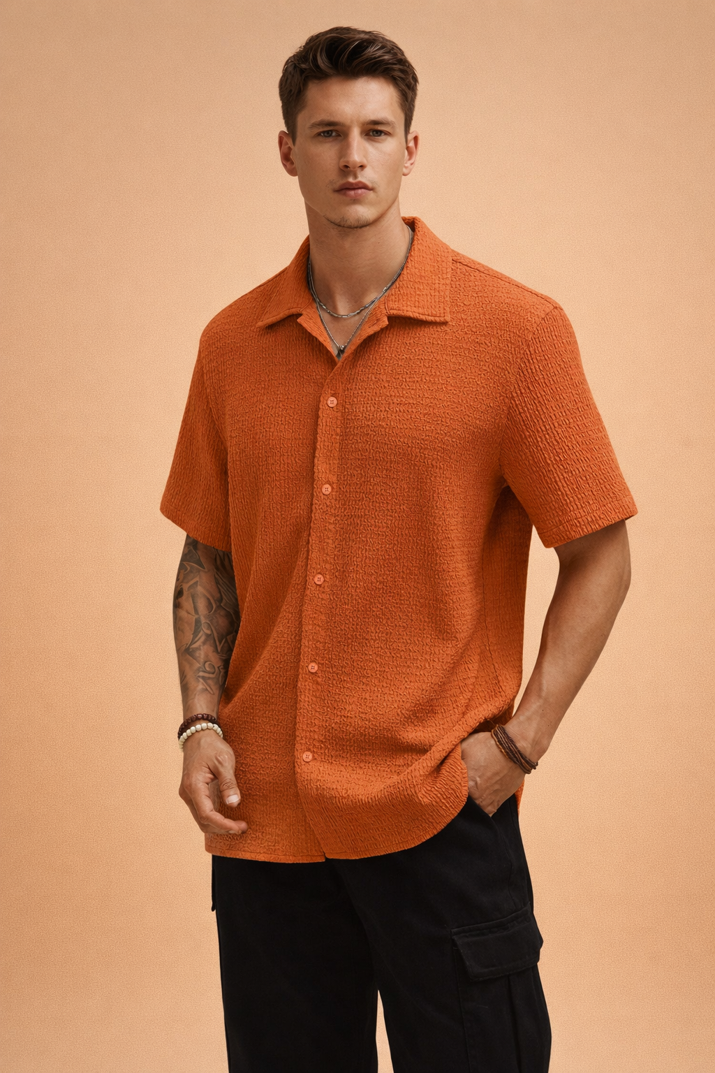 Model wearing men's orange short-sleeve textured button-up shirt with black cargo pants.