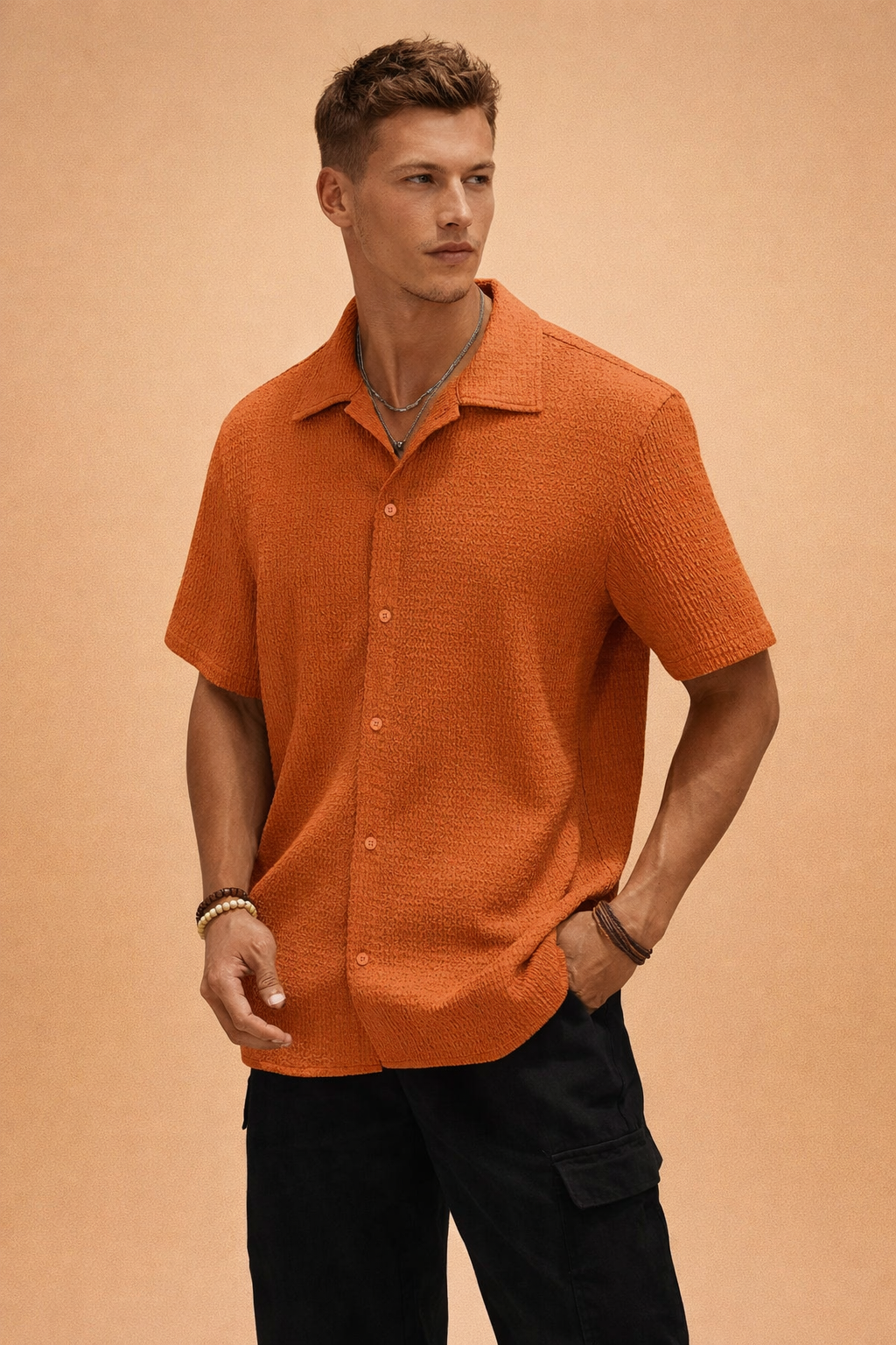 Close-up portrait of model wearing a textured short-sleeve shirt in terracotta orange.