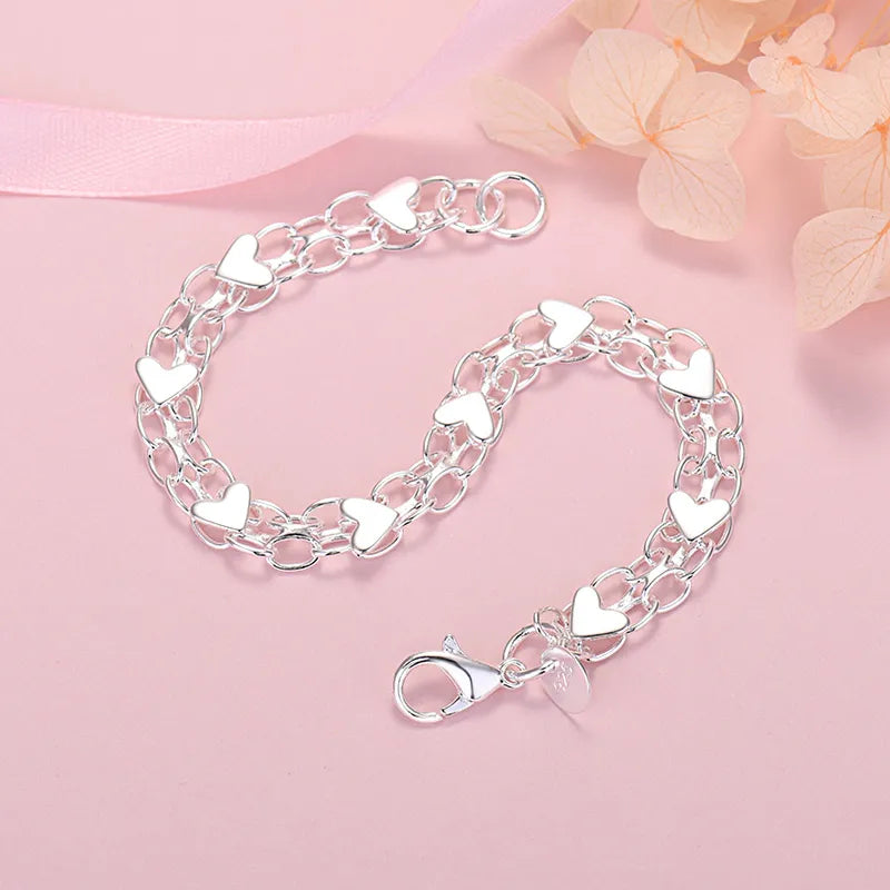 Close-up of silver heart link bracelet on pink background with flowers