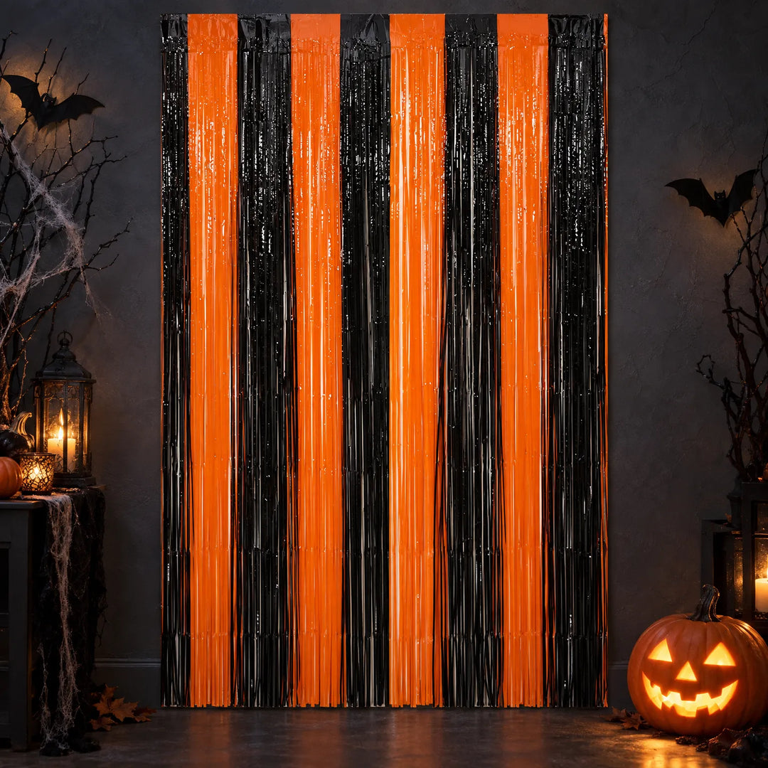 Metallic orange and black fringe wall curtain hanging in a dimly lit Halloween themed room with pumpkins.