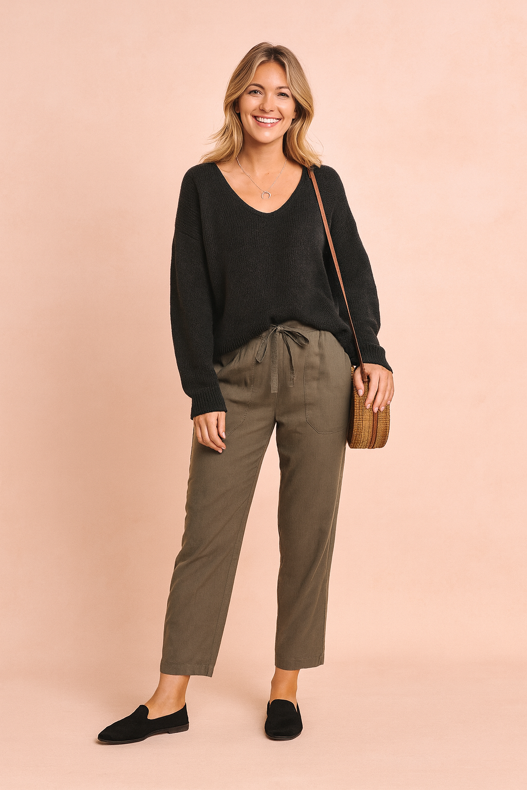 Model wearing a black V-neck knit sweater with olive drawstring trousers and loafers.