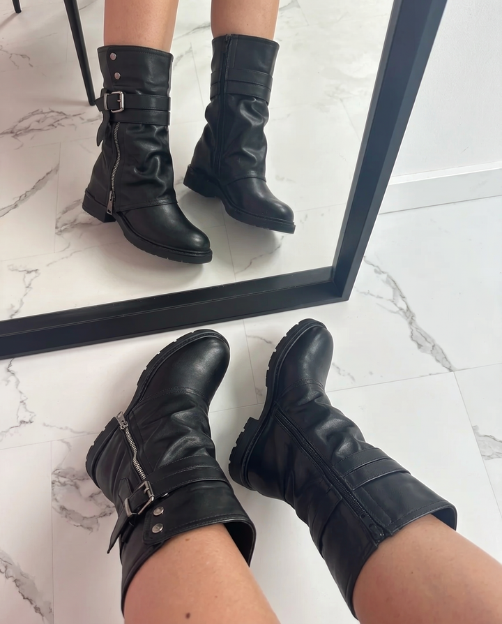 Close-up of women's black biker boots with metallic hardware and slouchy design