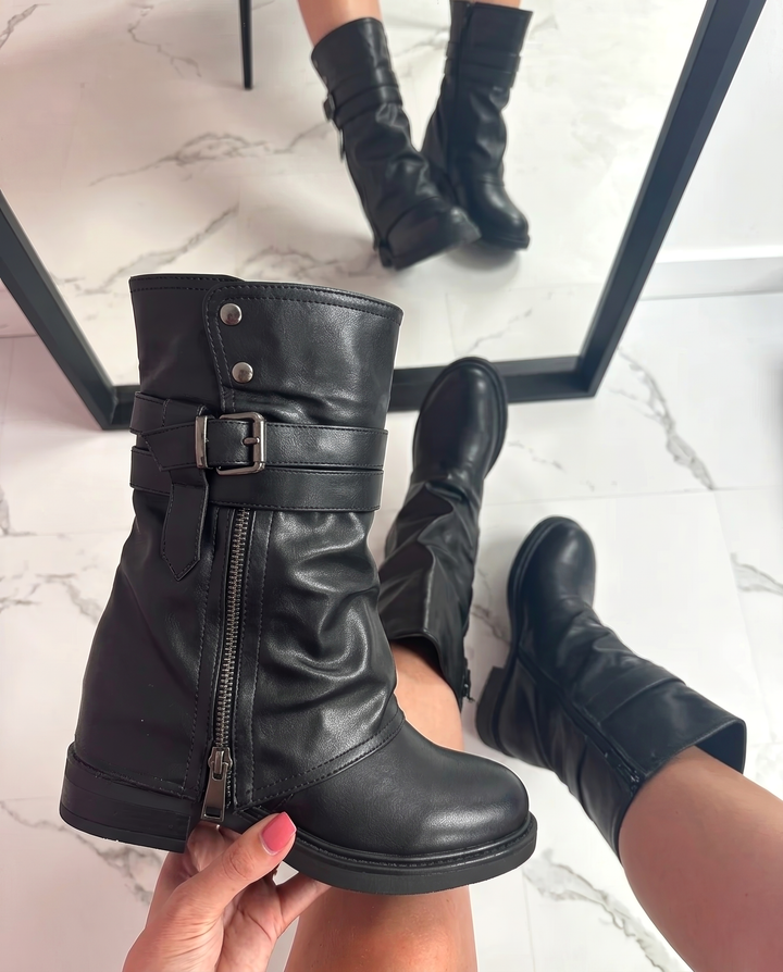 Women's black biker boots showcasing side zipper and buckle details worn with mirror reflection