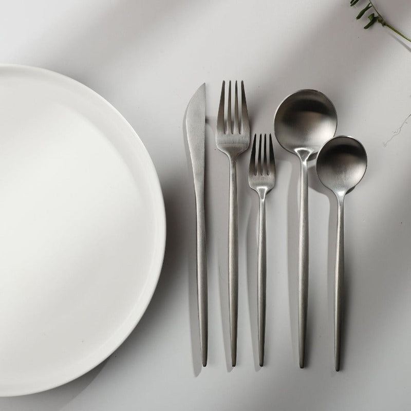 Complete stainless steel tableware set for a four-person dining setup