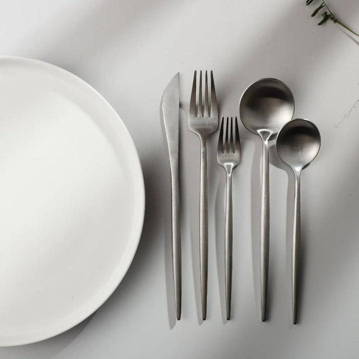 Complete stainless steel tableware set for a four-person dining setup