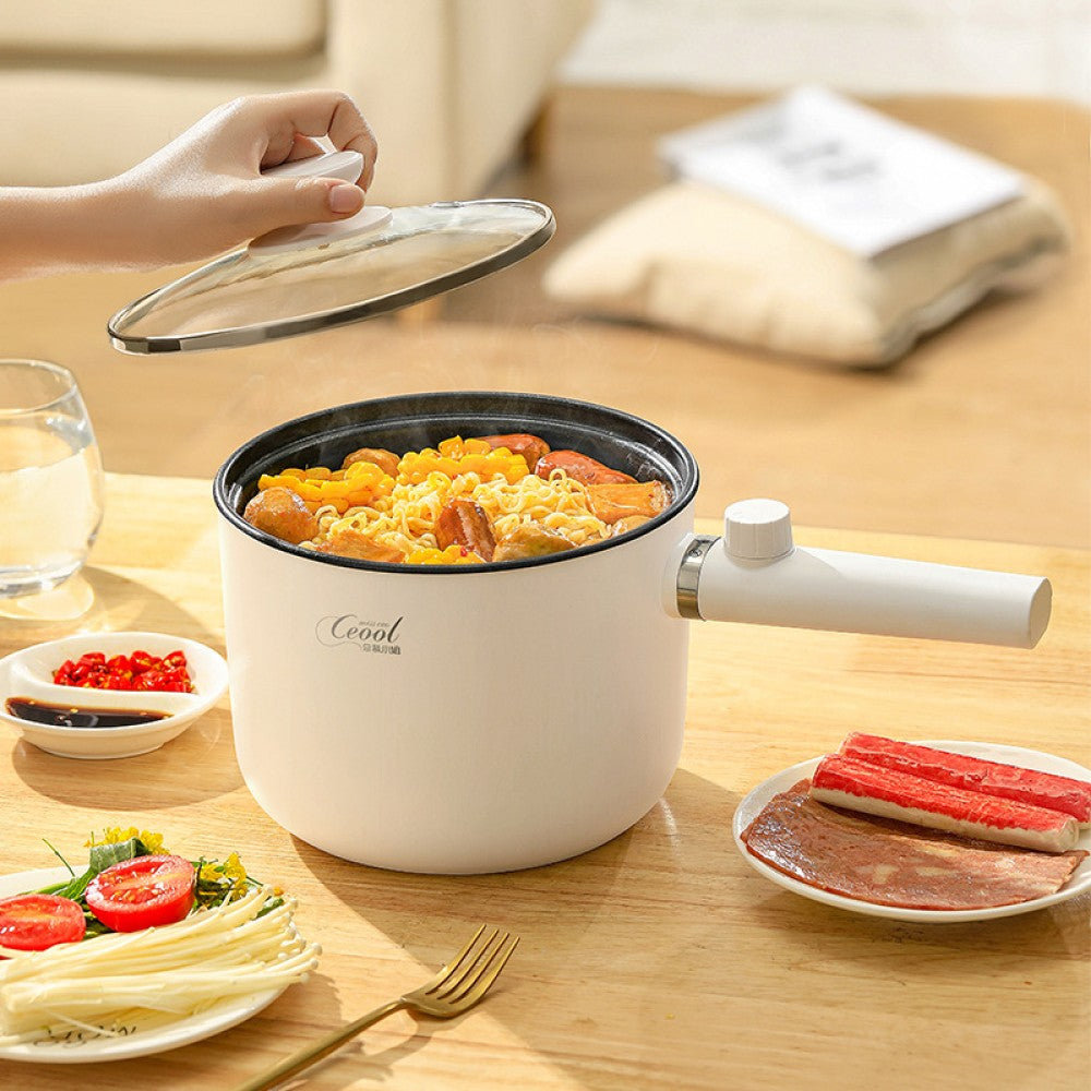 Close-up of the electric cooking pot with glass lid open, showing cooked noodles on a wooden table.