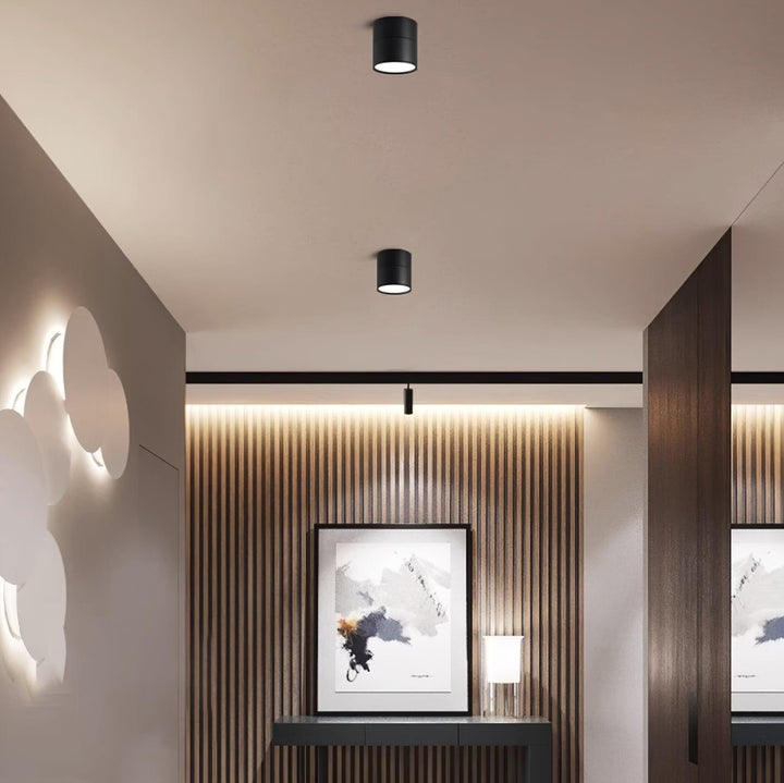 Black cylindrical LED ceiling spotlights installed in a modern hallway corridor