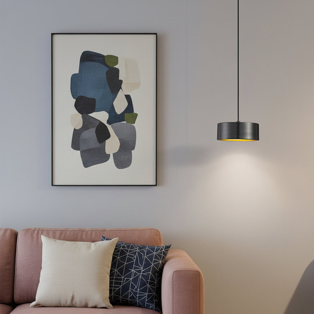 Modern black iron hanging lamp glowing above a living room sofa with framed wall art.