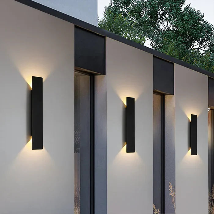 Sleek vertical exterior wall lanterns casting warm up and down light