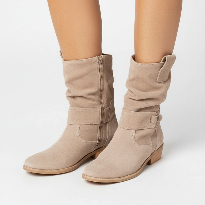 Side view of beige women's ankle boots with a relaxed slouch shaft and low heel against a neutral background