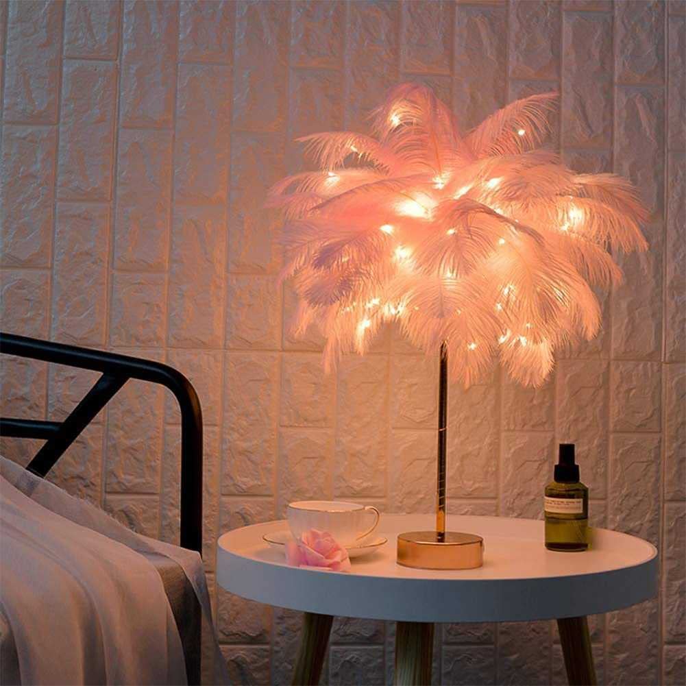 Pink OstrichGlow feather night light glowing on a bedside table
