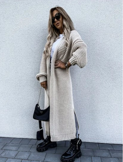 Full length view of a woman in a beige cardigan paired with black jeans and boots